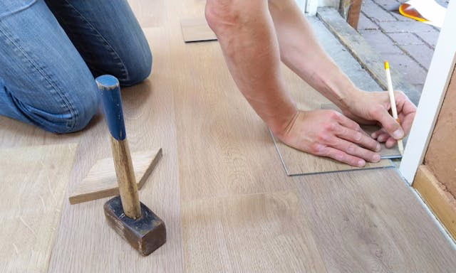 person holding a pencil while fixing flooring
