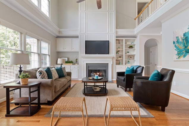 White living room with a grey couch and two black leather arm chairs