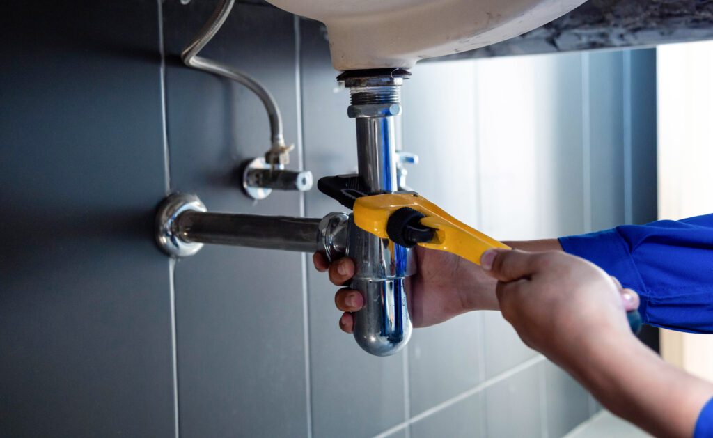a plumber fixing a leak under a sink