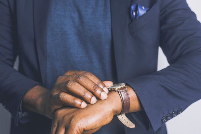 person in a blue suit looking at their watch