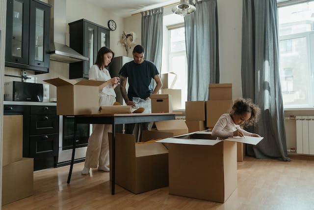 a couple and their child unpacking moving boxes in their new kitchen
