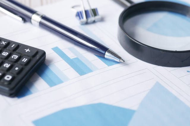 a calculator magnifying glass and a pen on a bunch of graphs