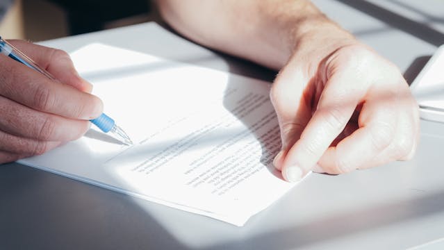 person signing a document with a pen